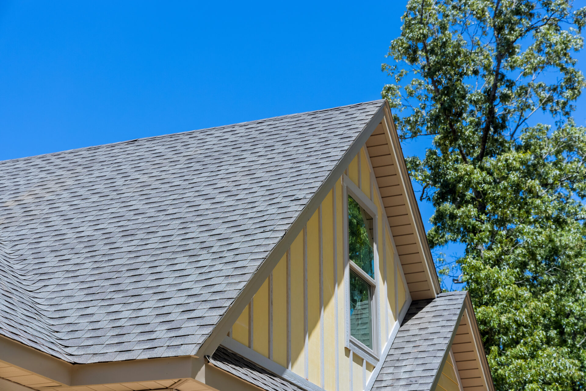 A yellow house with an asphalt shingle roof